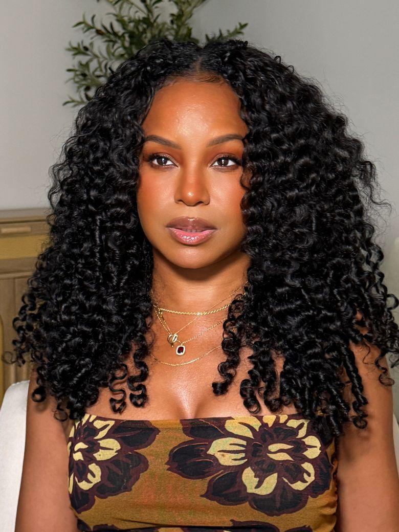 A model displays the UNice InvisiBlend V part Jerry Curly& Kinky Curly Wig Invisi Drawstring Human Hair, showing a model with long curly hair and a brown dress and kinky.