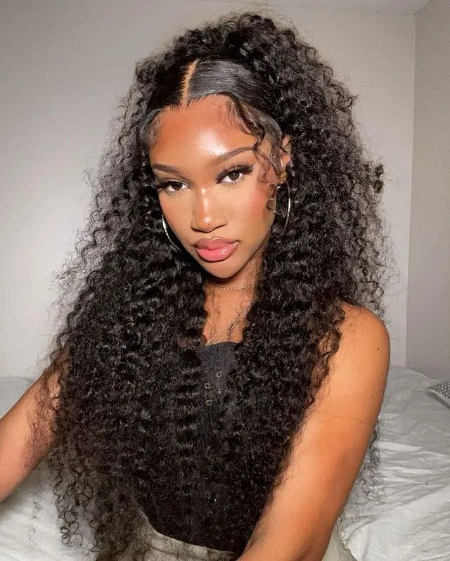 A model displays the UNice 200% Density 7x5 Bye Bye Knots Wig Glueless Lace Jerry Curly Wig With Bleached, showing a model with long curly hair sitting on a bed.