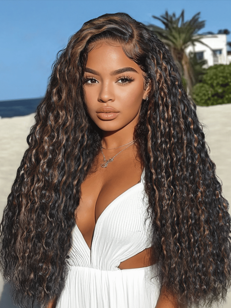 A model displays the UNice Bye Bye Knots 7x5 Lace Water Wave Black Wig With Golden Brown Highlights &, showing a model with long curly hair standing on the beach.