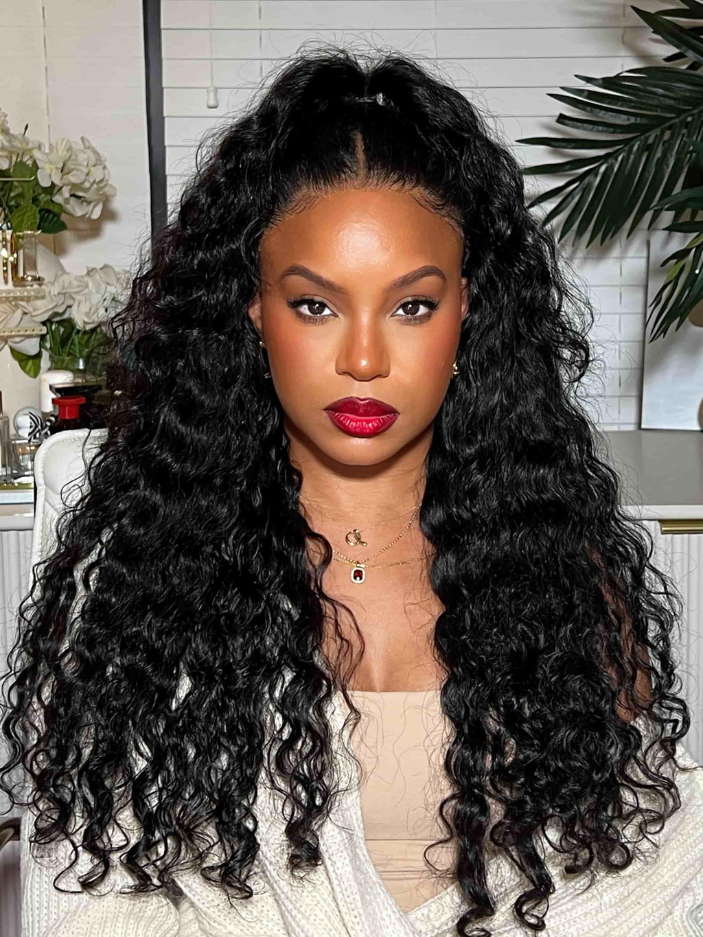 A model displays the UNice 7x5 Bye Bye Knots Wig Quick Glueless & HD Lace Wet & Wavy Water Wave Invisible, showing a model with long curly hair wearing a white sweater.