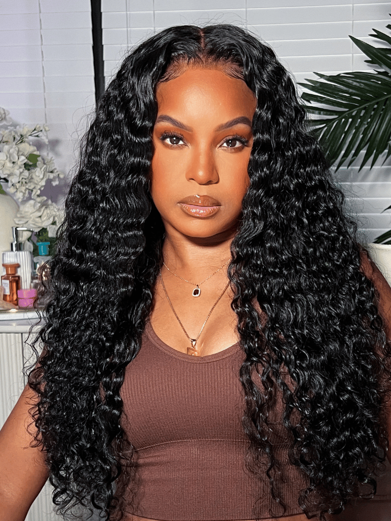 A model displays the Unice 7x5 Pre-cut Lace Put On & Go No Glue Wig Water Wave With Baby Hair 150% Density, showing a model with long black hair and a brown top.