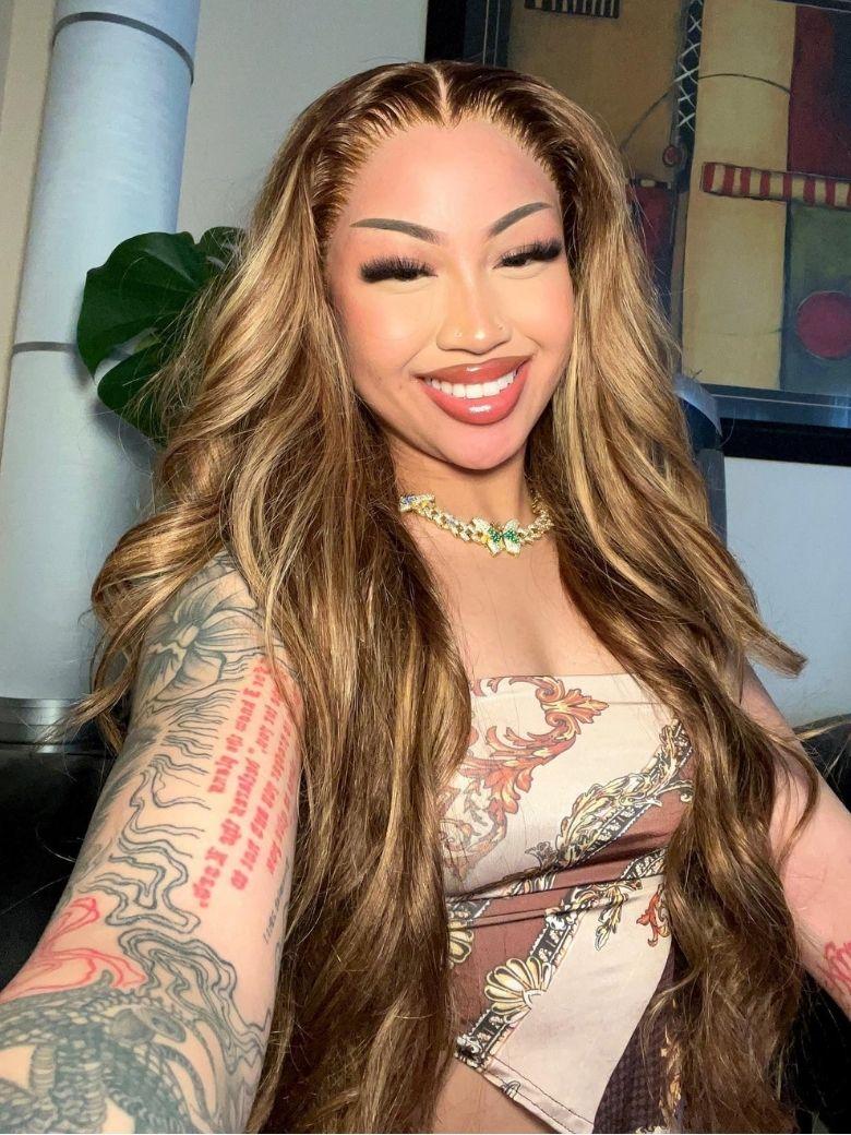 A model displays the UNice 7x5 ByeBye Knots Wig Glueless Lace Honey Blonde 3D Body Wave Wig With Bleached, showing a model with long hair and tattoos and body wave.