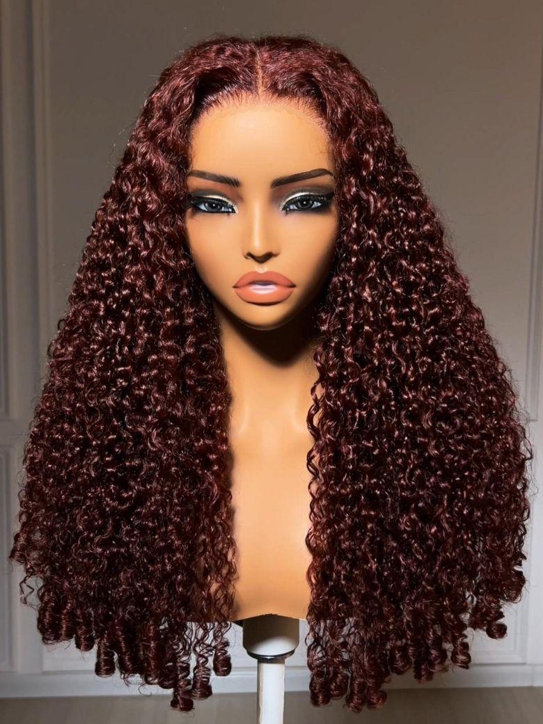 A model displays the UNice Bye Bye Slip 7x5 Lace Warm Brown with Beige Blonde Ribbon Highlights Layered wig, showing a model with blonde hair and a black top sitting.