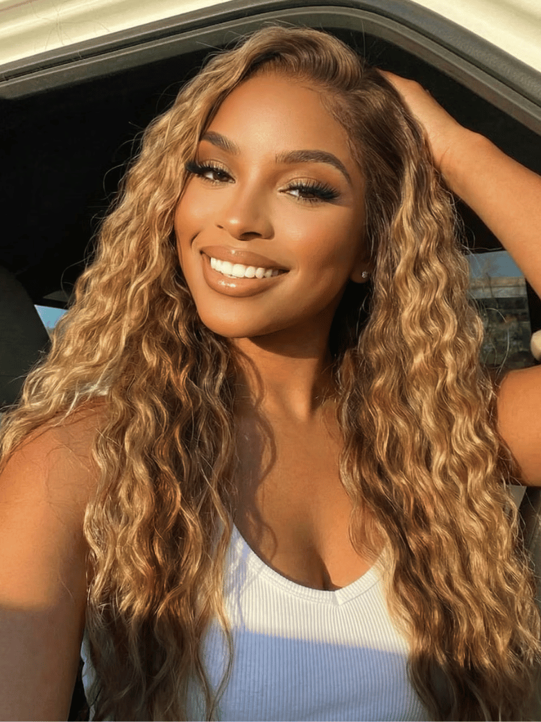 A model displays the UNice 13x4 Bye Bye Slip Lace Frontal Caramel Brown With Honey Blonde Highlights, showing a model with long curly hair and a white tank top and water.