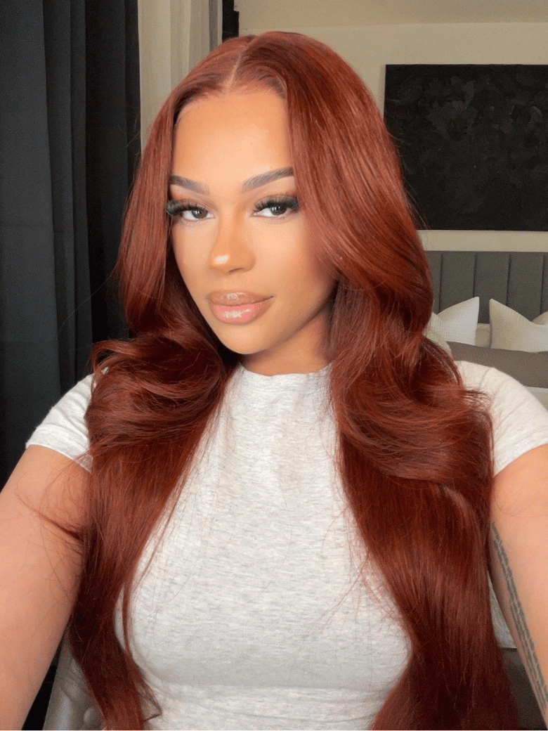 The UNice 7x5 Bye Bye Slip Wig Glueless Lace 150% density Flattering Sun-Kissed Warm visual image position 2 shows a model with long red hair and a white shirt | body.