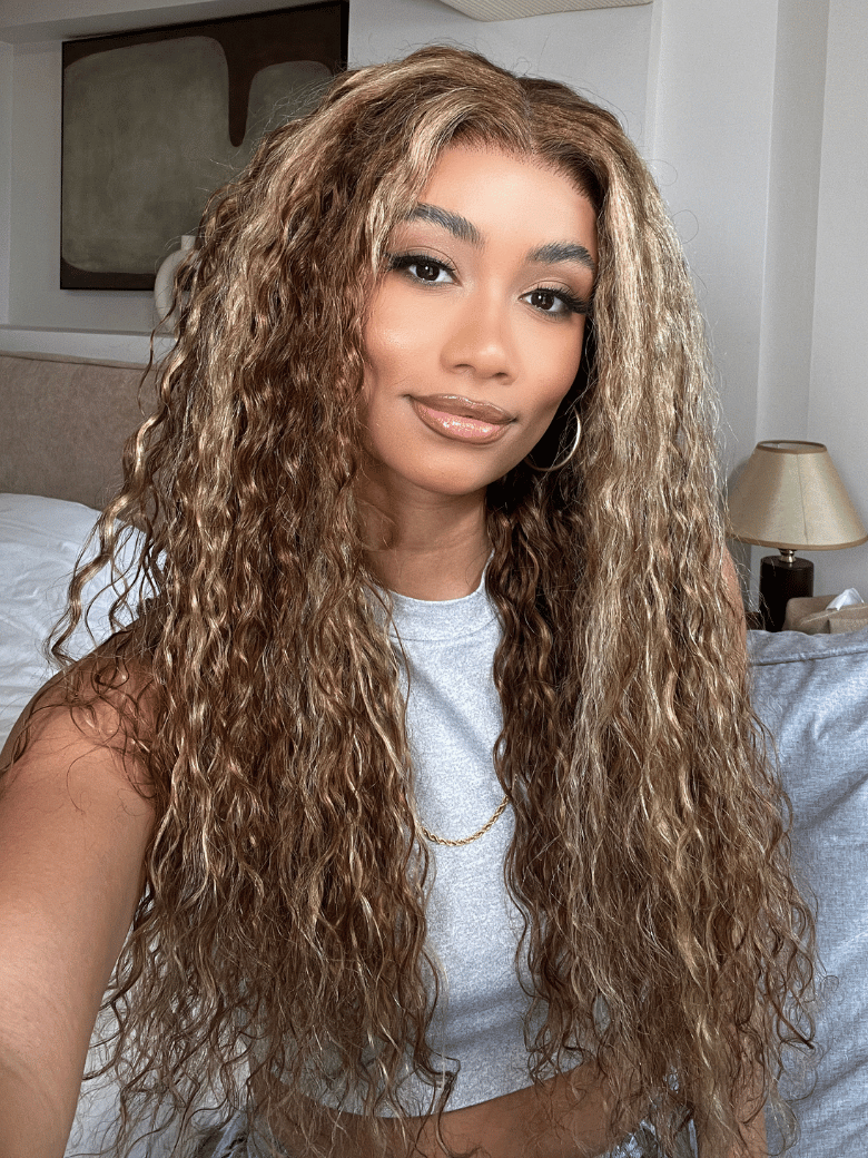 A model displays the UNice Pre-Everything 13x4 Lace Frontal Honey Blonde Highlights Jerry Curly Wig, showing a model with long hair sitting on a bed and jerry curl.