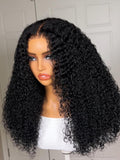 A model displays the UNice 7x5 Lace Bye Bye Slip Glueless Wig Black Kinky Curly Wig With 4C Baby Hair, showing a model with long curly hair wearing a pink shirt.