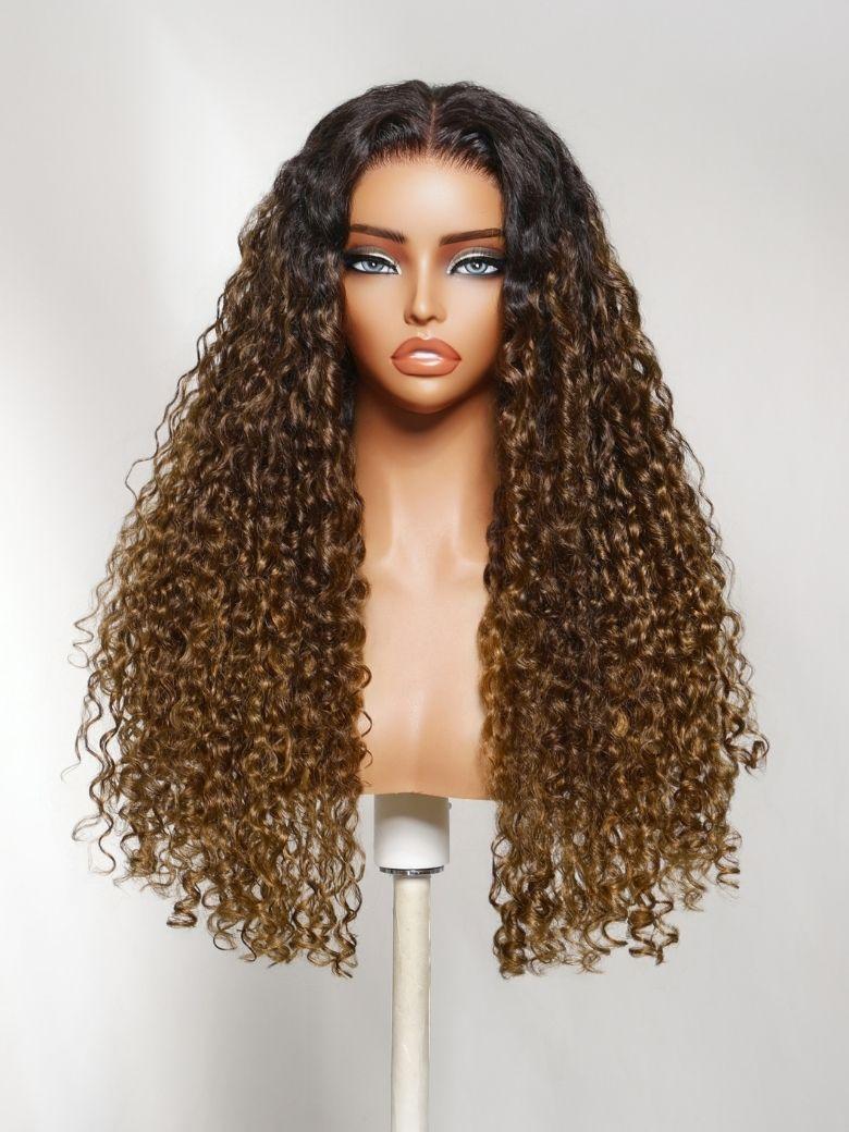 A model displays the UNice Bye Bye Slip 7x5 Lace Glueless Sun-Kissed Honey Brown Ombre Tight Spiral wig, showing a wig with long curly hair on a mann and ombre, 7x5.