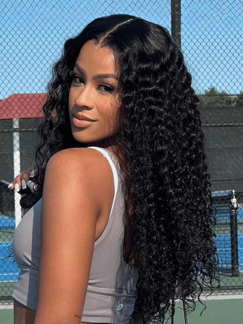A model displays the UNice 7x5 & 6x4.5 Pre Cut Lace Put On And Go Black Water Wave Air Wig, showing a model with long black hair standing on a tennis court and water.