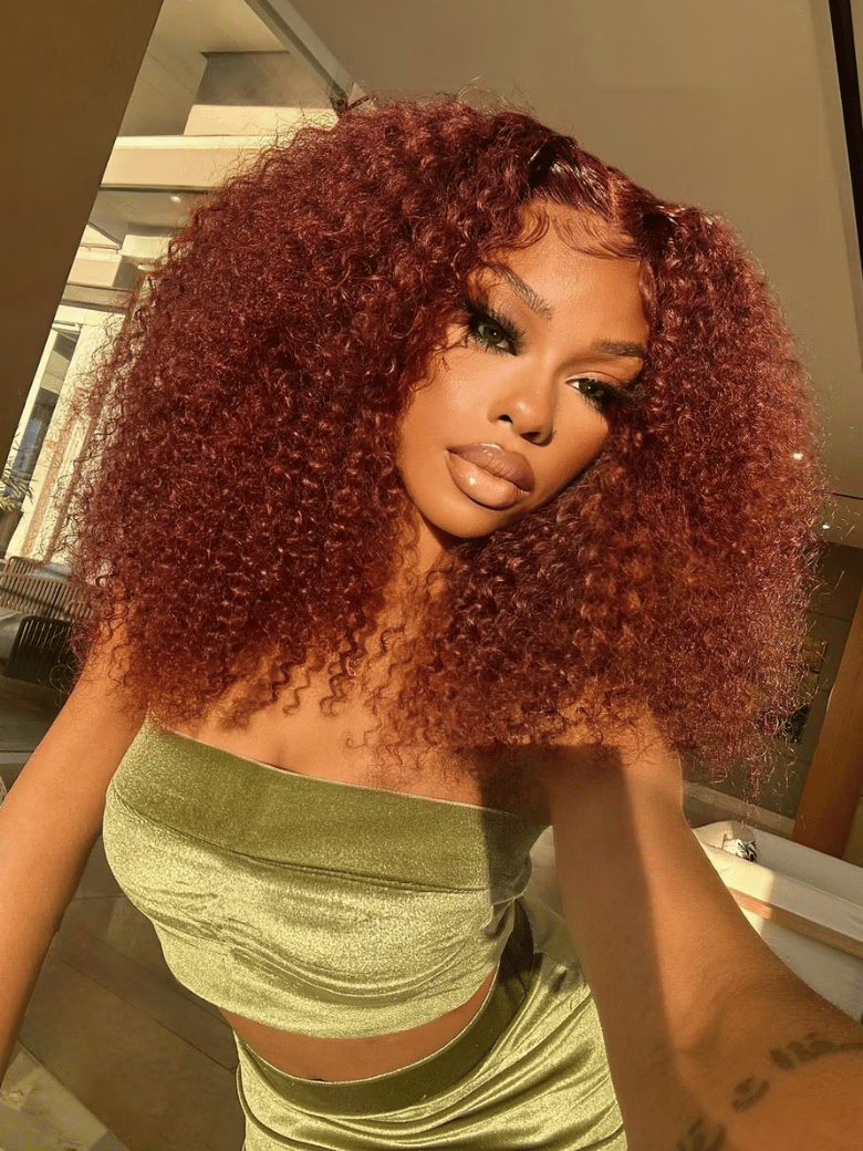 A model displays the UNice Ins Only 7x5 Bye Bye Knots Reddish Brown Kinky Curly & Straight & 13x4 wig, showing a model with red hair and a green top and loose wave.