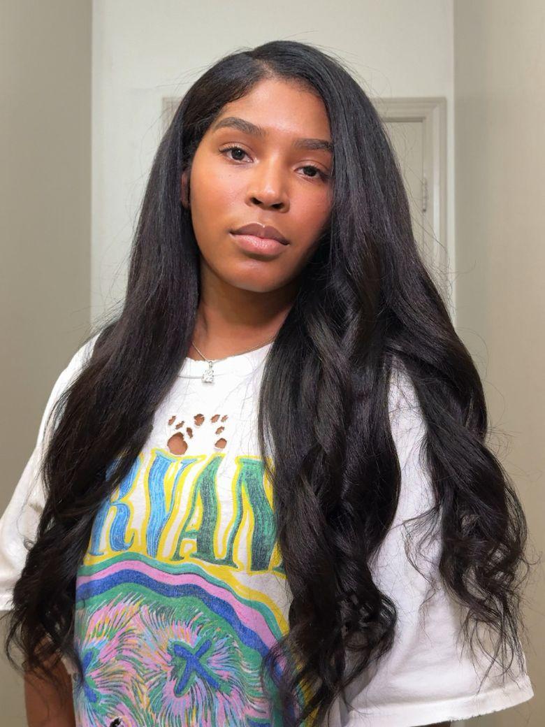 A model displays the UNice Kinky Straight When Wet InvisiBlend V Part Silk Press To Blow Out Kinky wig, showing a girl with long black hair and a white shirt and kinky.