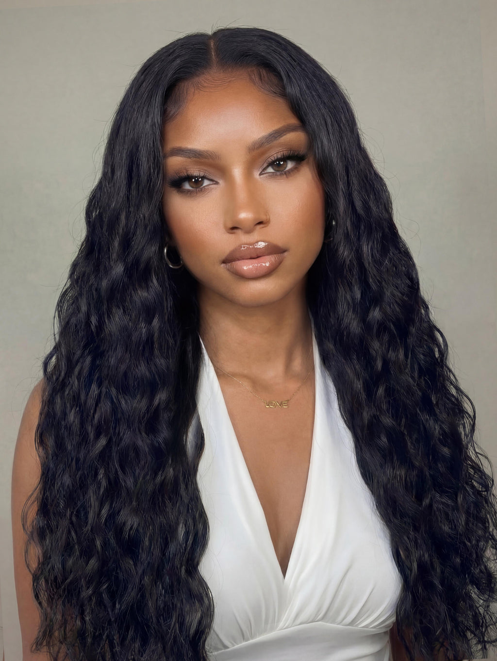 A model displays the UNice Invisi Drawstring " 13x4 Pre-Everything Natural Black Micro Water Wave Wig, showing a model with long black hair wearing a white dress.