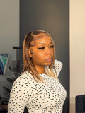 A model displays the UNice 13x4 Lace Front Black With Medium Auburn Brown Y2K Highlights Bob Wig, showing a model with a black and white polka print shirt and highlight.