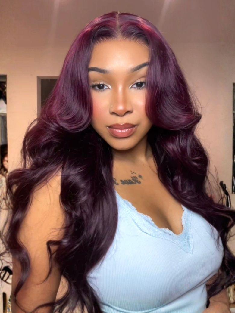 A model displays the UNice Invisi Drawstring 13x4 Pre-Everything Lace Purple Black Cherry Loose Wave wig, showing a model with long purple hair and a blue top and loose.