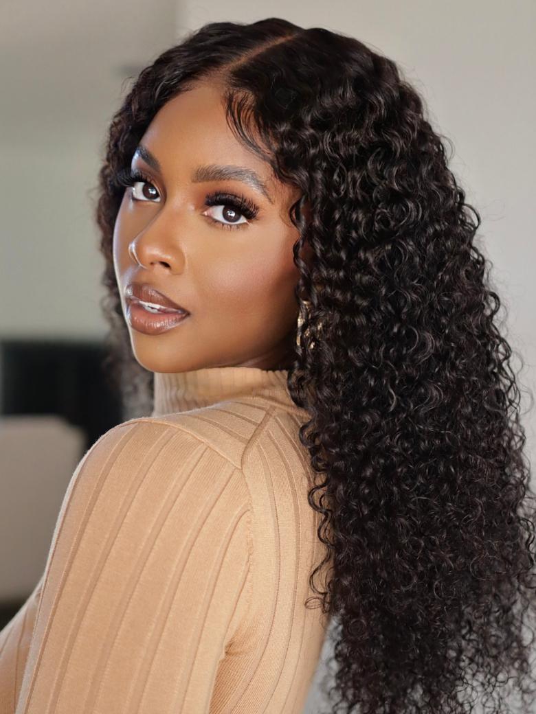 A model displays the UNice EasiContour V Part Minimal Glueless Curly Glueless Wig Invisi Drawstring Human, showing a model with long curly hair wearing a tan sweater.