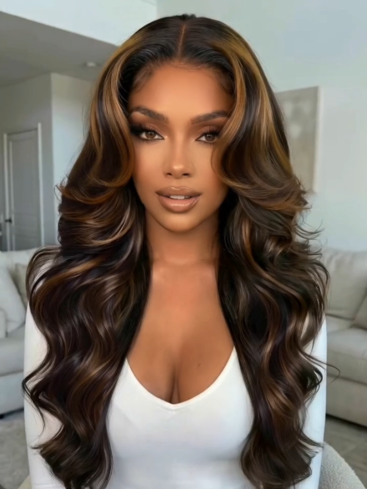 A model displays the UNice 7x5 Bye Bye Slip Lace Black with Golden Brown Highlights Body Wave Wig with, showing a model with long brown hair and a white shirt and body.