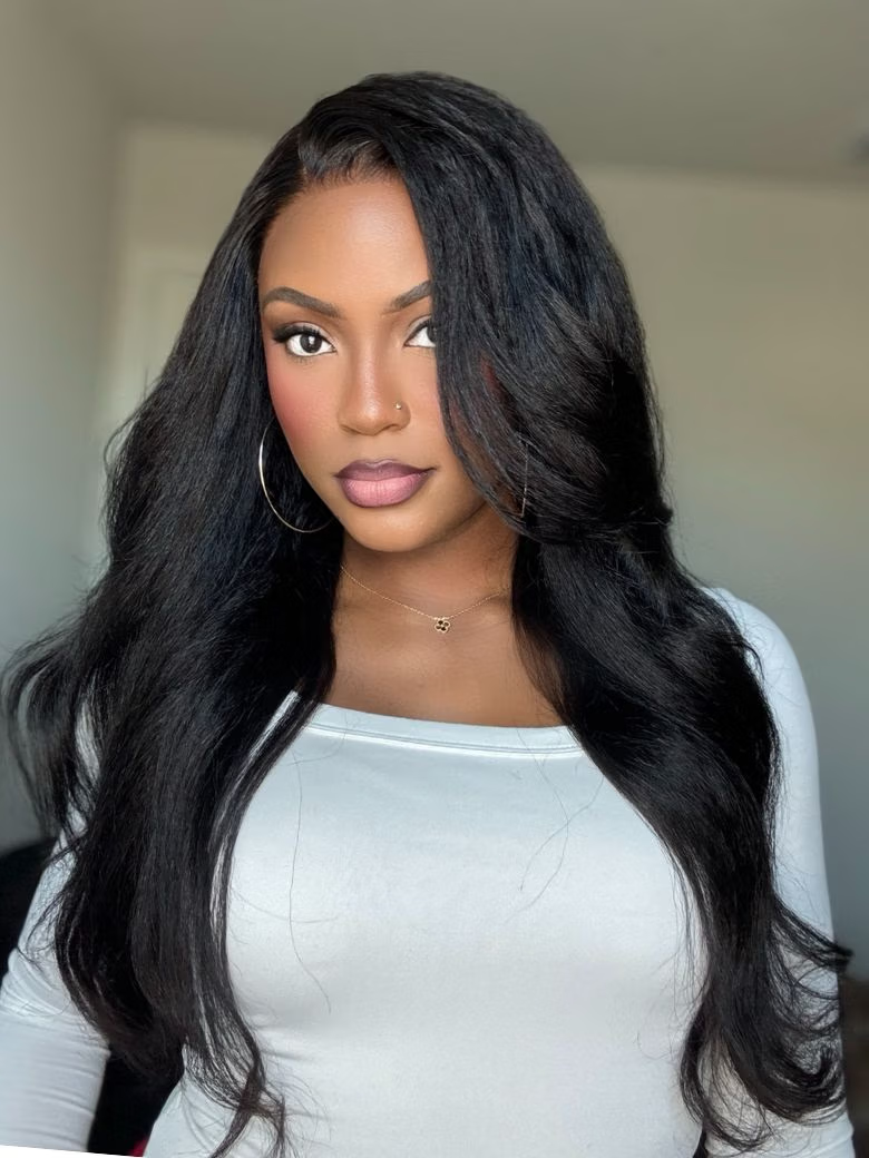 A model displays the UNice Kinky Straight When Wet InvisiBlend V Part Silk Press To Blow Out Kinky wig, showing a model with long black hair and a white shirt and kinky.