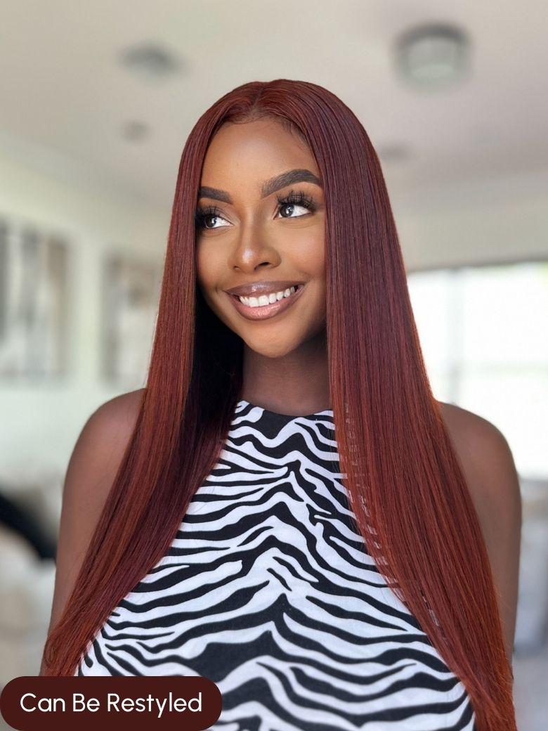 A model displays the UNice 7x5 Byebye Knots Lace Reddish Brown Body Wave Bleached Knots Blend Seamless Wig, showing a model with long red hair and a zebra print top.