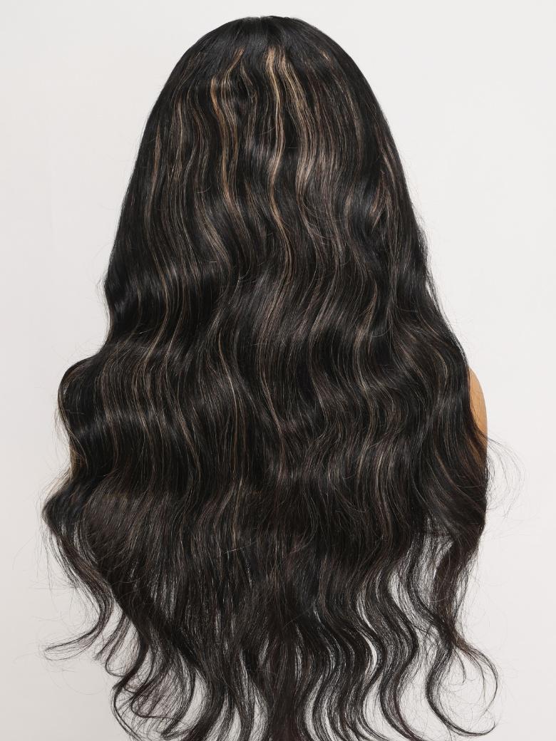 A model displays the UNice Bye Bye Knots Wig 7x5 Glueless Lace Black With Blonde Highlights 3D Body Wave, showing a model with long black hair and a brown top and body.