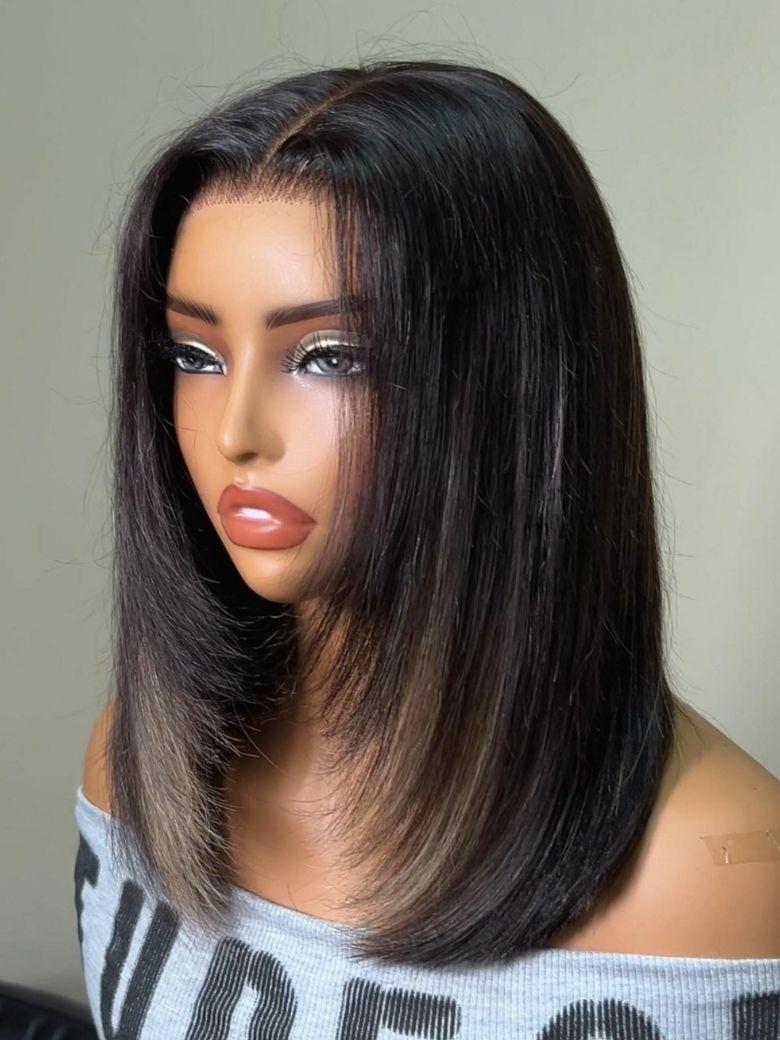 A model displays the UNice Bye Bye Slip 7x5 Lace Warm Brown with Beige Blonde Ribbon Highlights Layered wig, showing a model with blonde hair and a black top sitting.