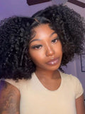 A model displays the UNice 7x5 Lace Bye Bye Slip Natural Black Afro Kinky Curly with Finger Coil Ends wig, showing a model with long curly hair and a white shirt.