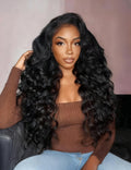 A model displays the UNice 20 Inch 180% Density Full Lace Deep Wave Transparent Lace Human Hair Wig, showing a woman sitting on a couch wearing a brown sweater and jeans.