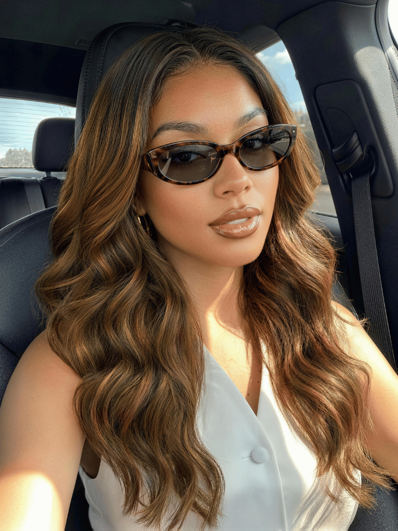 A model displays the UNice 7x5 Bye Bye Slip Balayage Highlight Body Wave & Curtain Bangs Wig - Glueless, showing a woman in a car with sunglasses on and body wave.