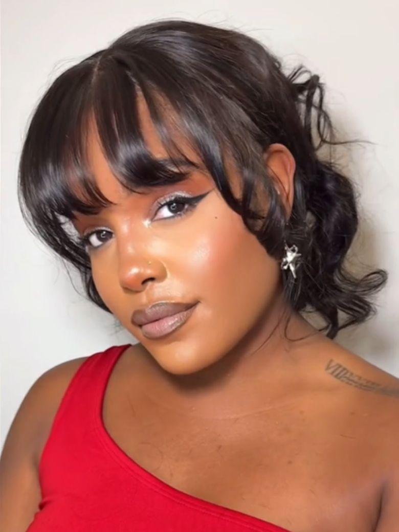 A model displays the UNice 7x5 & 13x4 Bye Bye Slip Pull & Go Black Fluffy Loose Wave Wispy Bangs Glueless, showing a model with a red top and black hair and loose wave.
