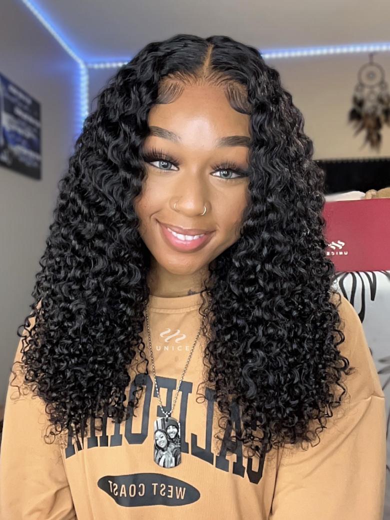 A model displays the UNice 7x5 Bye Bye Slip 150% Density Jerry Curly Wig With Bleached Invisible Knots, showing a model with long curly hair wearing a brown sweatshirt.