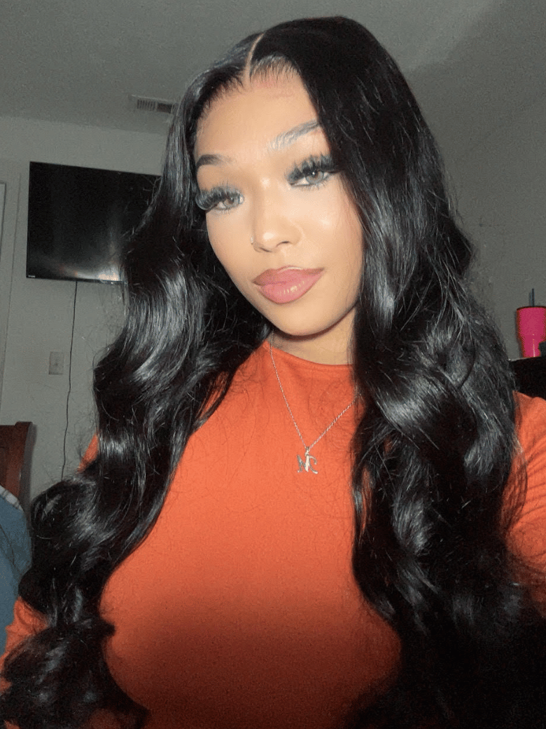 A model displays the UNice 13x4 HD Lace Bye Bye Slip Body Wave Wig - Human Hair Glueless Pull & Go Fit, showing a model with long black hair and a red shirt and body.