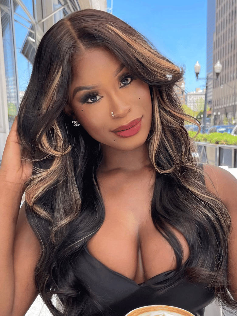 A model displays the UNice Bye Bye Knots Wig 7x5 Glueless Lace Black With Blonde Highlights 3D Body Wave, showing a model with long brown hair and a black dress holding.