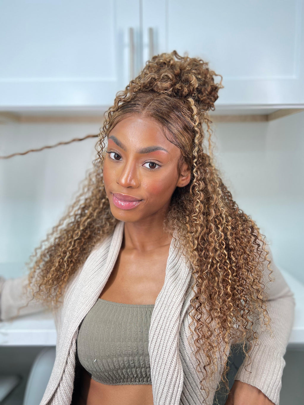A model displays the UNice 180% Density Reddish Brown Water Wave Or Honey Blonde Jerry Curly 13x4 wig, showing a model with long curly hair and a white sweater and water.